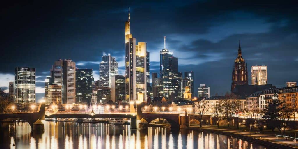 Skyscraper skyline at night in Frankfurt, a modern city with a reflective river, ideal for escort services in an urban environment.