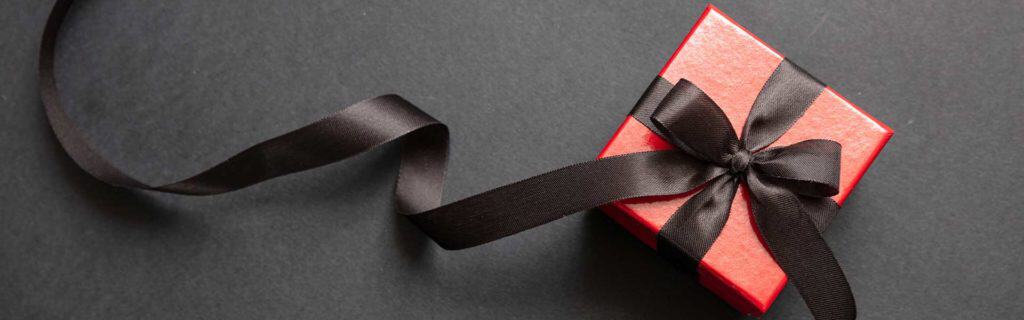Red gift box with black ribbon, luxury gifts, exclusive gift ideas, suitable services for escort service, sensual surprise for special moments.
