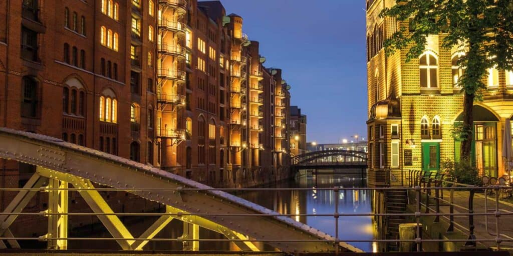 Attractive escort ladies in Berlin at night, stylishly dressed, against the historical backdrop of the city with illuminated buildings and waterways.